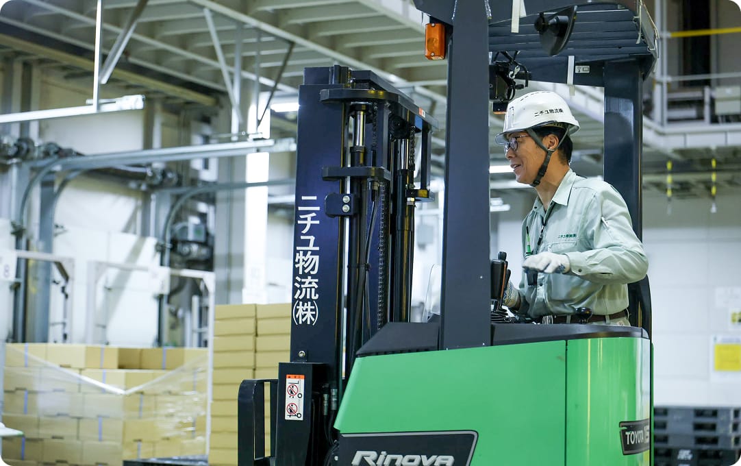 フォークリフトに乗る作業スタッフの写真