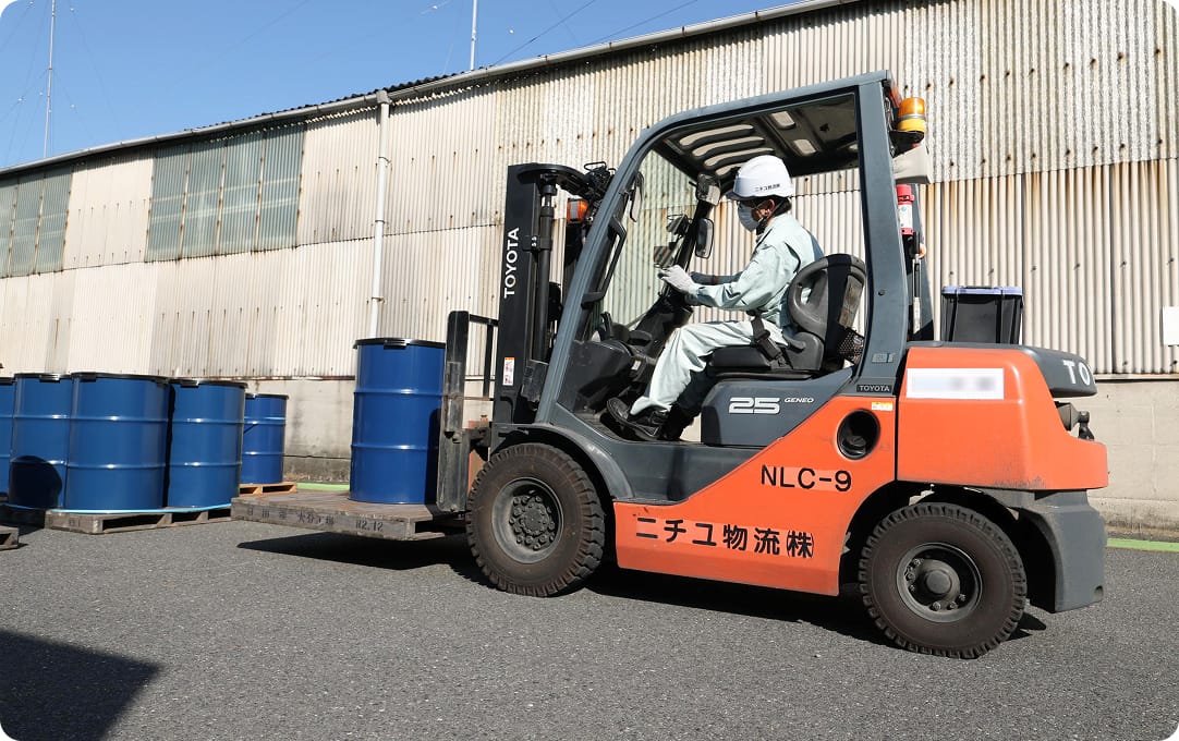 フォークリフトでドラム缶を運んでいる写真